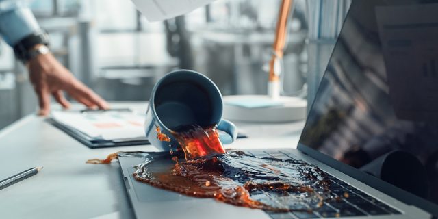 Eine Kaffeetasse wird über einen Laptop gekippt, symbolisiert das Risiko eines Datenverlusts durch einen Datenbruch.