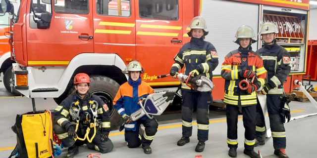 Feuerwehrleute posieren mit ihrer Ausrüstung für ein Gruppenfoto.